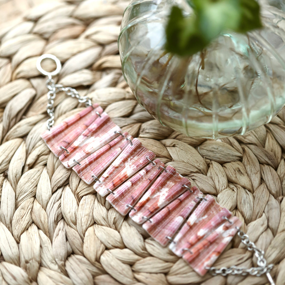 Bracelet entier en coquillage rose corail marbré de blanc, maillons trapèzes striés, chaîne et fermoir en T argentés, sur un set tressé